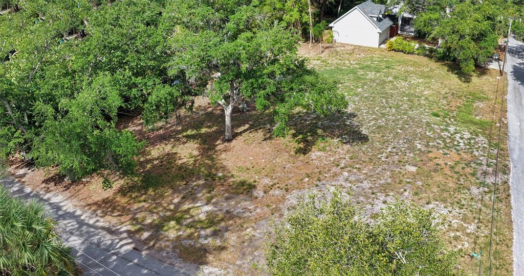 An aerial view shows a vacant, grassy residential lot with several trees and a nearby house — TURKS CAP PLACE, SARASOTA, FL