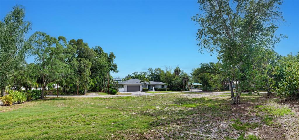 A wide, grassy vacant lot sits in front of a single-story house with a garage — TURKS CAP PLACE, SARASOTA, FL