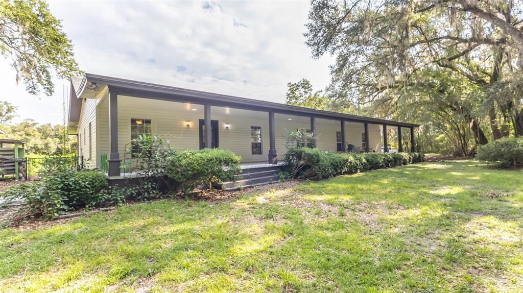 A single-story house with a long covered front porch and dark support columns — 22304 NE 35TH AVENUE, MELROSE, FL