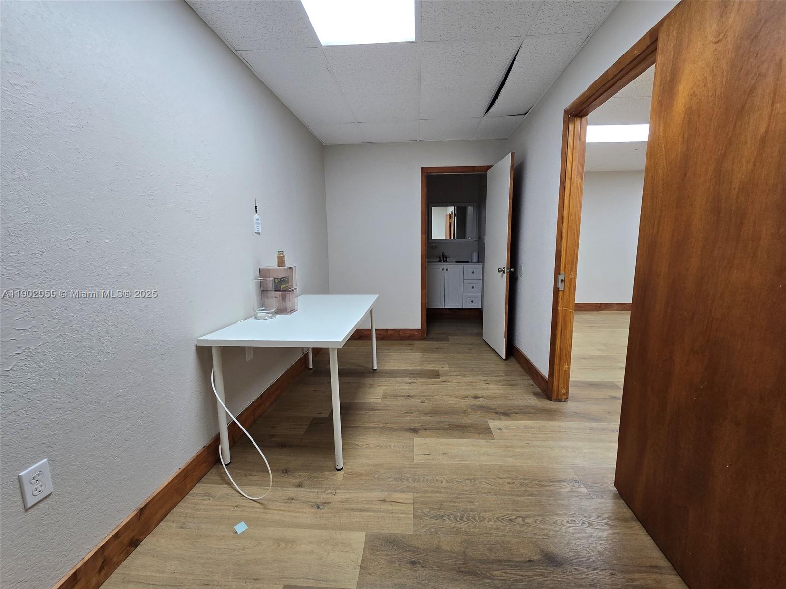 A small office room features wood-look flooring, a white desk, and an attached bathroom — 3580 NW 32nd St, Miami FL 33142, MIAMI, FL