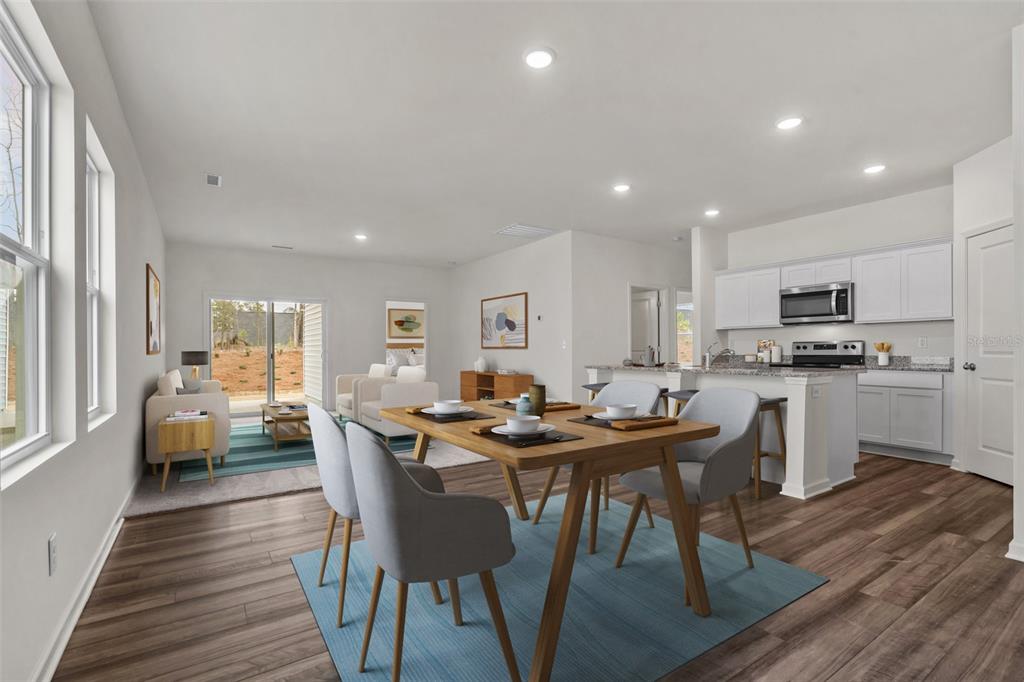 This rendering shows an open-concept living and dining area with light wood floors and white cabinets — 36094 CANELLI WAY, DADE CITY, FL