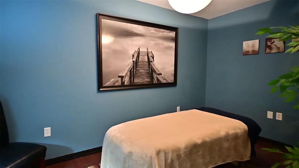 A massage room features blue walls, a treatment table, and a large framed pier photograph — 245 E PARK AVENUE, LAKE WALES, FL