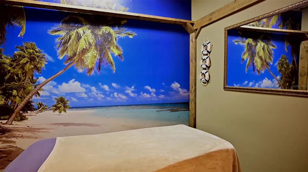 A massage room features a tropical beach mural, a massage table, and a wall mirror — 245 E PARK AVENUE, LAKE WALES, FL