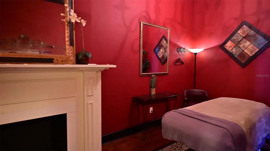 A massage room features red walls, a fireplace, a treatment table, and decorative wall mirrors — 245 E PARK AVENUE, LAKE WALES, FL