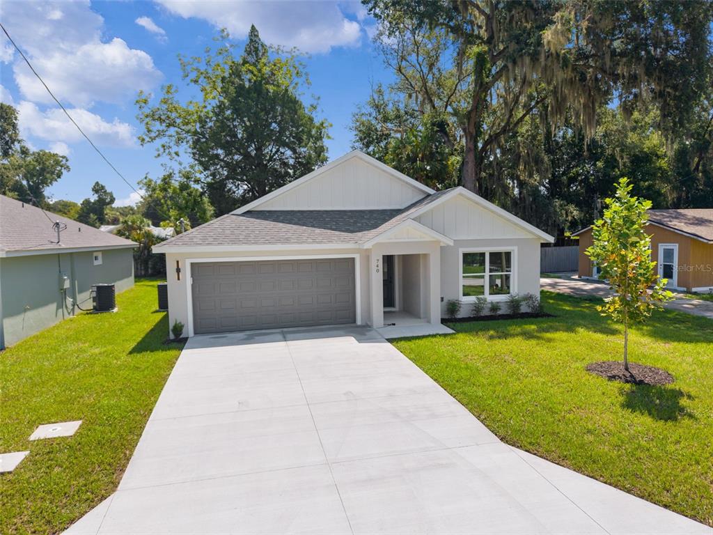 A single-story house with a gray garage door, white siding, and a concrete driveway — 740 POWELL STREET, WILDWOOD, FL