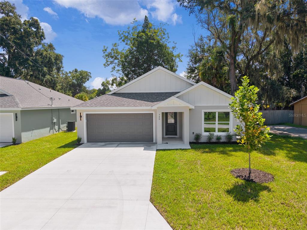 A single-story house with a gray garage, white siding, and a concrete driveway — 740 POWELL STREET, WILDWOOD, FL