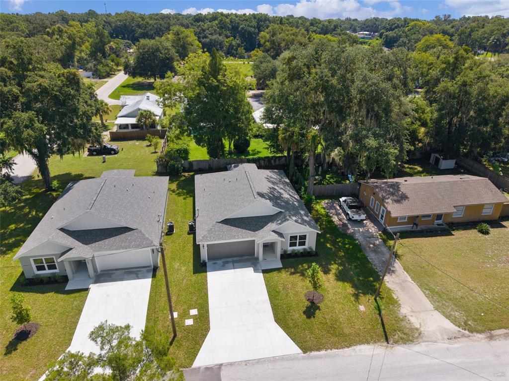 An aerial view shows three houses with driveways and lawns surrounded by mature trees — 740 POWELL STREET, WILDWOOD, FL