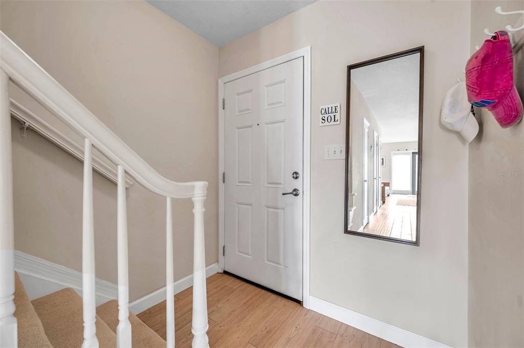 An entryway features a white door, a staircase with a railing, and a wall mirror — 4766 SNOOK DRIVE SE, ST PETERSBURG, FL