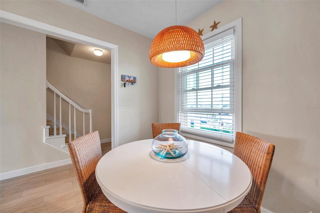 A dining area features a round white table, wicker chairs, and a woven pendant light — 4766 SNOOK DRIVE SE, ST PETERSBURG, FL