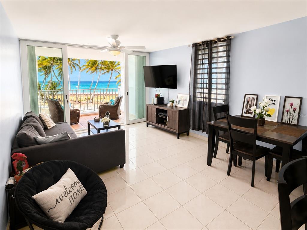 A living and dining area with tile floors, a balcony, and a view of the ocean — 3 OCEAN DR. UNIT 201, LUQUILLO, PR