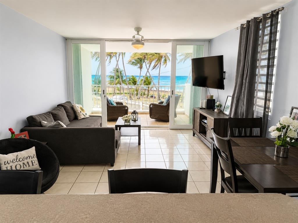 A living and dining area features tile floors, a balcony with ocean views, and furniture — 3 OCEAN DR. UNIT 201, LUQUILLO, PR