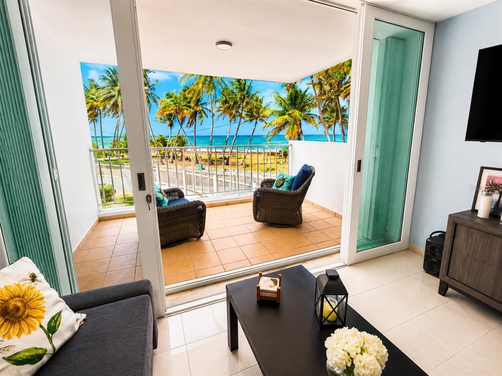A living room with a sliding glass door opening to a balcony overlooking the ocean — 3 OCEAN DR. UNIT 201, LUQUILLO, PR