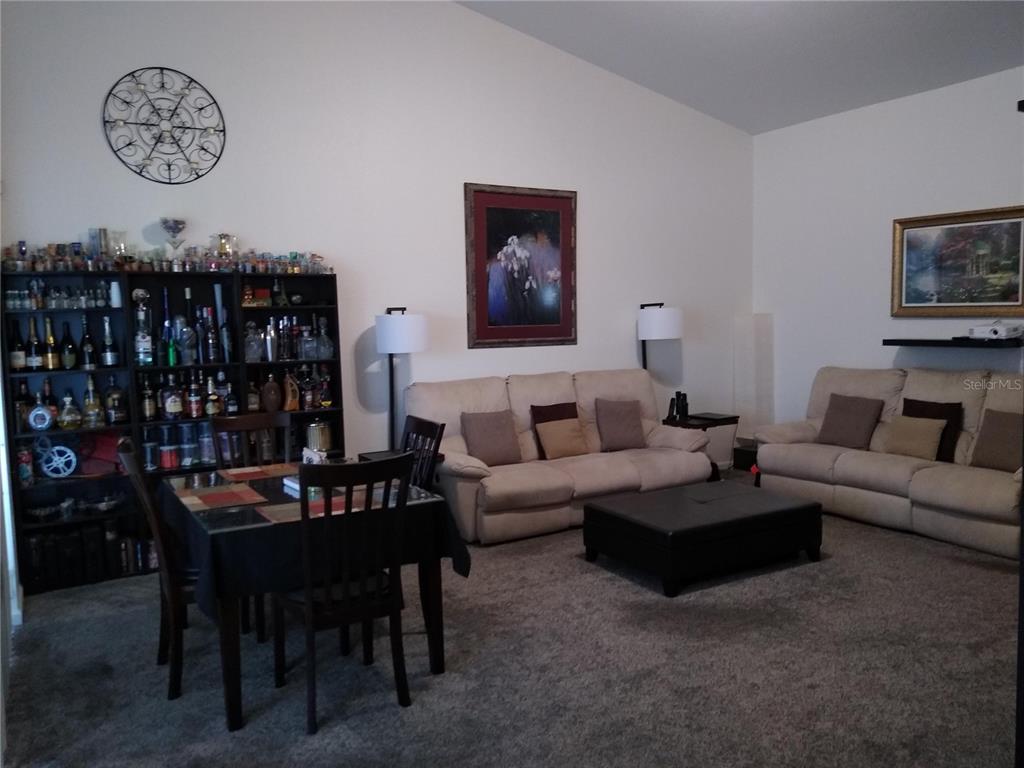 A living room features beige sofas, a dining table, and a large shelving unit — 1212 ROMANI AVENUE, DAVENPORT, FL