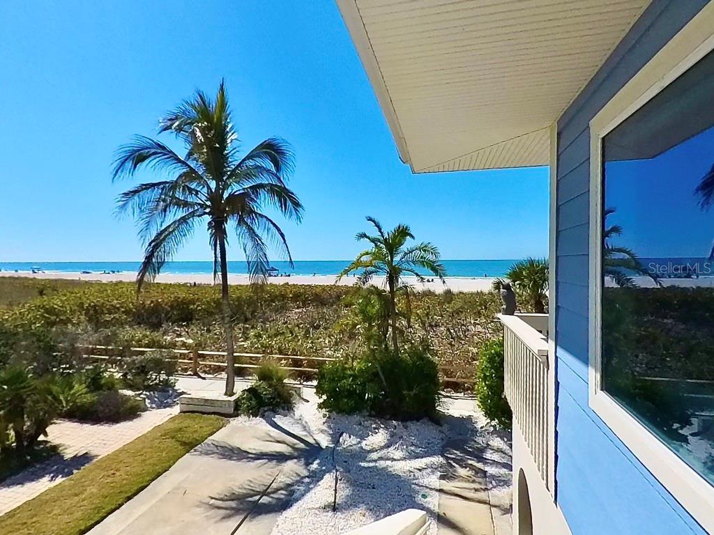 An elevated view of a beach and ocean from a blue house balcony — 103 PALM AVENUE, ANNA MARIA, FL