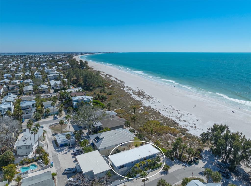 An aerial view shows a two-story beach house located directly along a sandy coastline — 103 PALM AVENUE, ANNA MARIA, FL