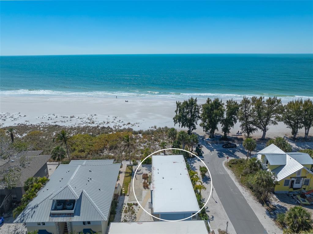 An aerial view shows a flat-roofed building situated between two houses near a sandy beach — 103 PALM AVENUE, ANNA MARIA, FL
