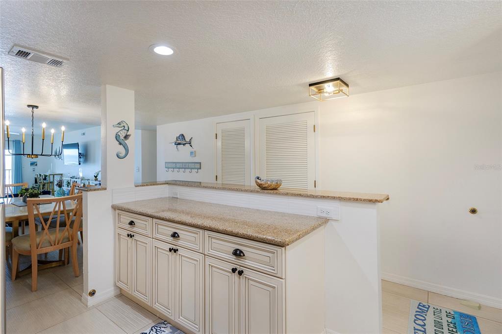 A kitchen pass-through counter with beige cabinets and granite countertops overlooks a dining area — 3807 S ATLANTIC AVENUE UNIT 302, DAYTONA BEACH, FL