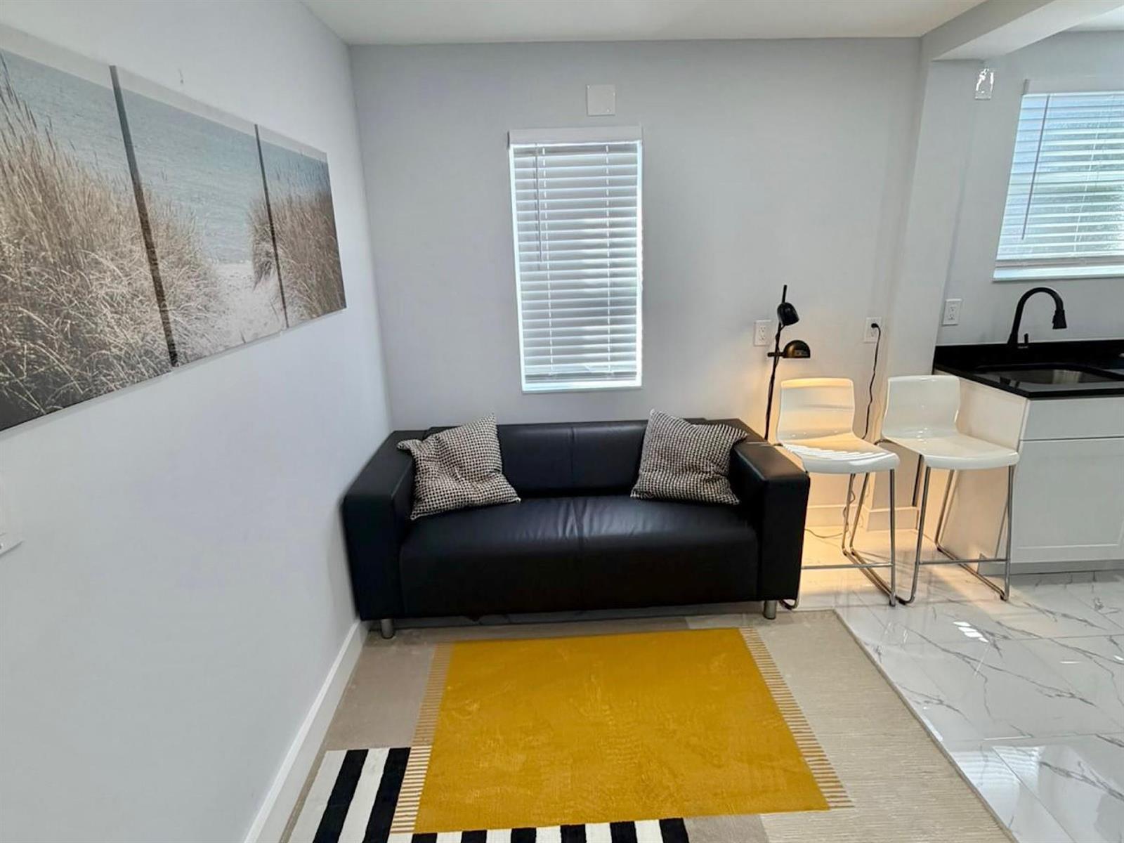 A small living area features a black sofa, a yellow rug, and two white bar stools — 851 NW 4th Avenue, Pompano Beach FL 33060, POMPANO BEACH, FL