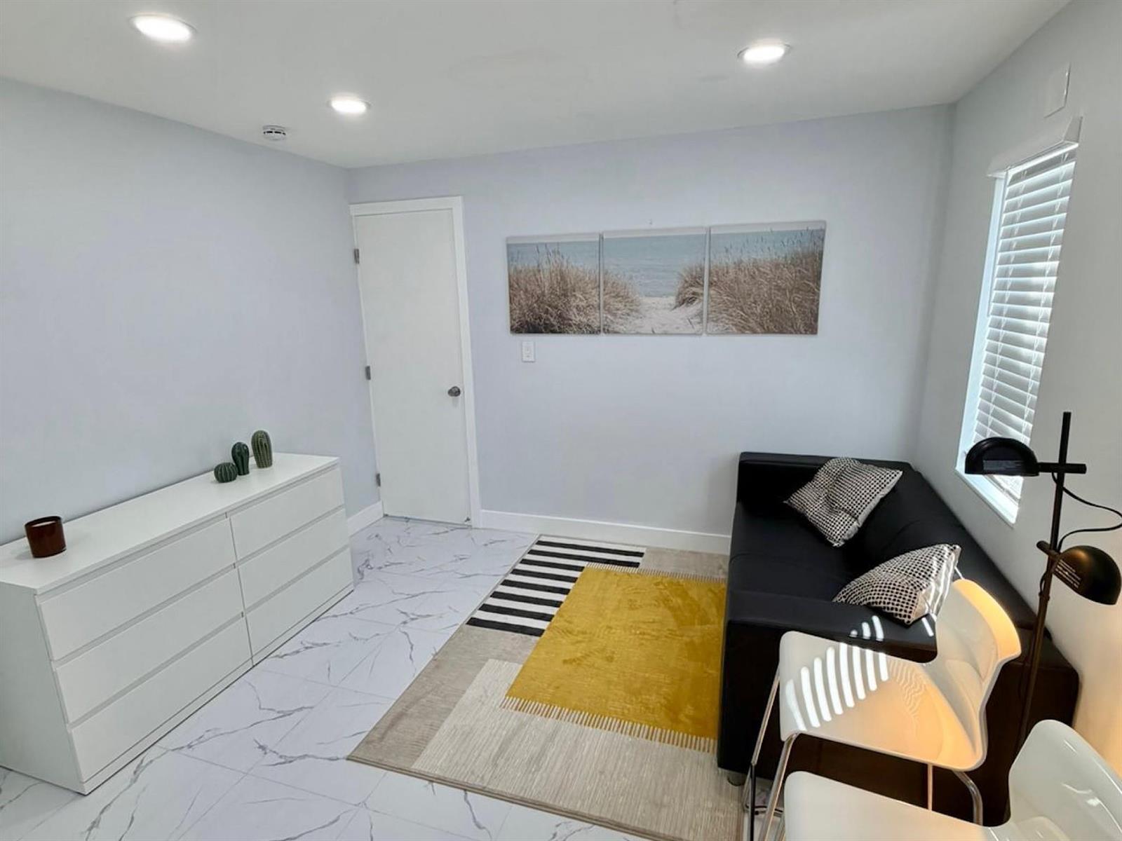 A room with white marble-style flooring, a black sofa, a yellow rug, and a white dresser — 851 NW 4th Avenue, Pompano Beach FL 33060, POMPANO BEACH, FL