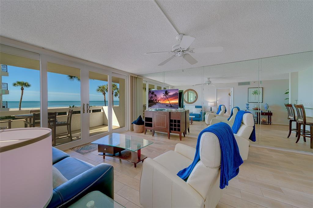 A living room with white tile floors, a ceiling fan, and sliding doors overlooking the ocean — 17900 GULF BOULEVARD UNIT 1B, REDINGTON SHORES, FL
