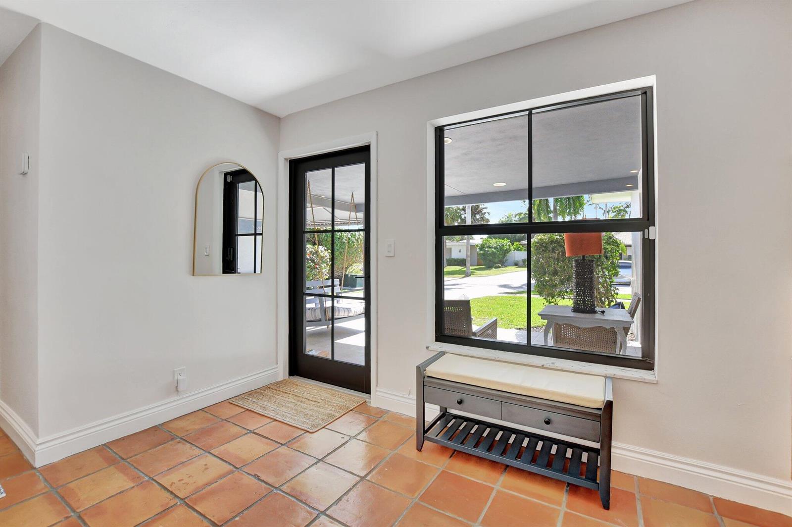 An entryway with terracotta tile flooring, a black-framed glass door, and a storage bench — 801 SW 5th Street, Boca Raton FL 33486, BOCA RATON, FL