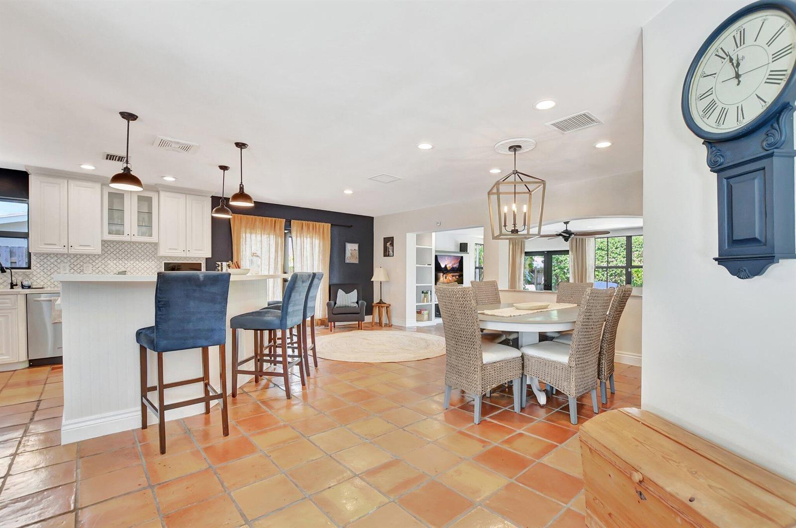 An open-concept kitchen and dining area features terracotta tile floors and blue accent walls — 801 SW 5th Street, Boca Raton FL 33486, BOCA RATON, FL