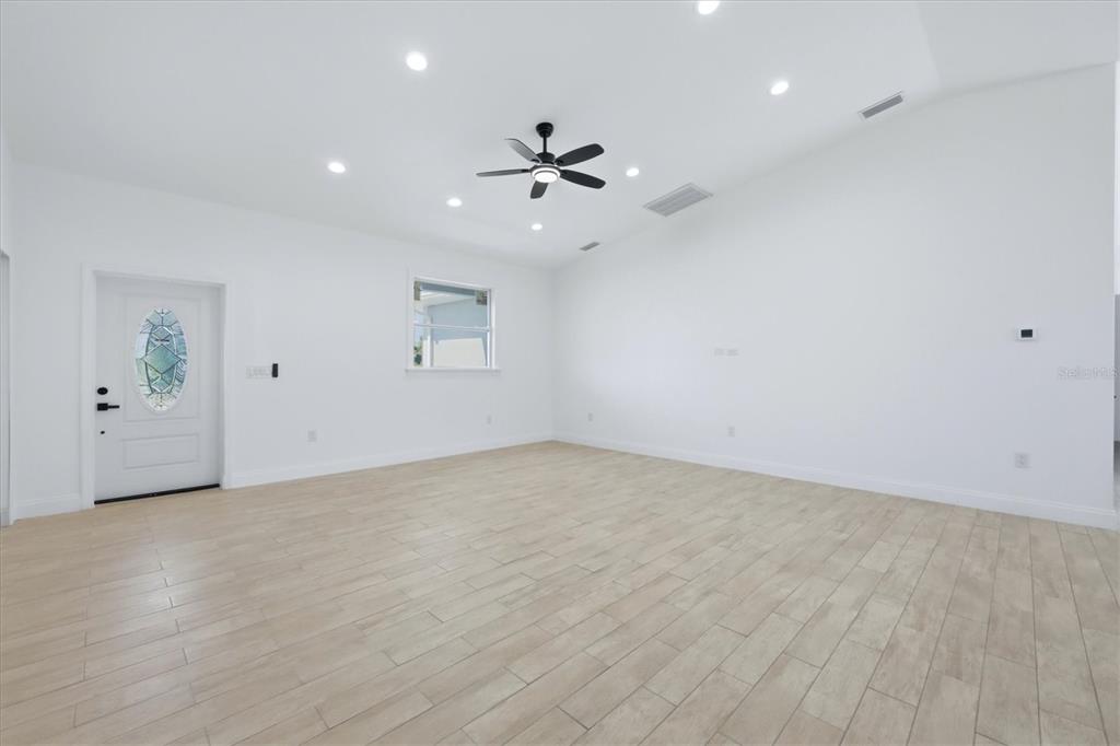An empty room with white walls, light wood-look tile flooring, and a ceiling fan — 8 BANK COURT, PLACIDA, FL