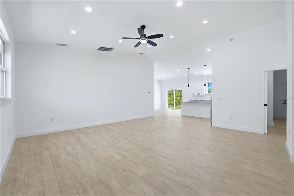 A spacious, bright living room features light wood-look tile flooring, recessed lighting, and a ceiling fan — 8 BANK COURT, PLACIDA, FL