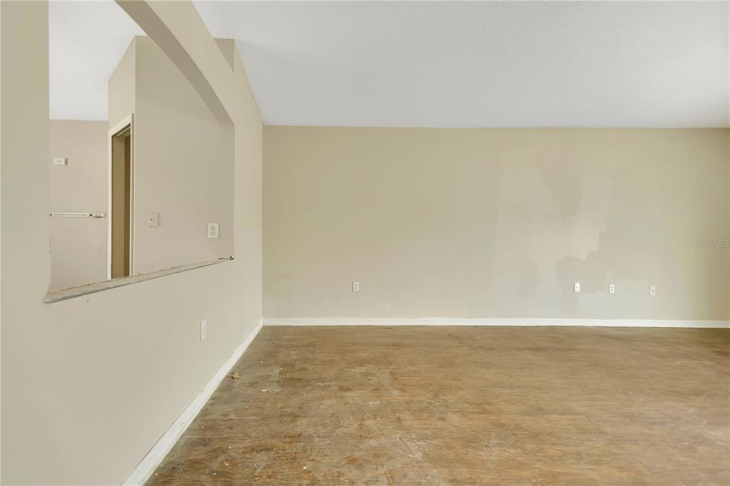 An empty room with beige walls, white trim, and wood-look flooring — 3941 WARBLER DRIVE, WINTER HAVEN, FL