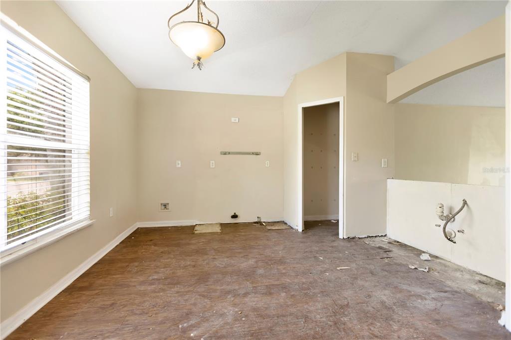 An empty room with beige walls, wood-look flooring, a light fixture, and exposed wall wiring — 3941 WARBLER DRIVE, WINTER HAVEN, FL