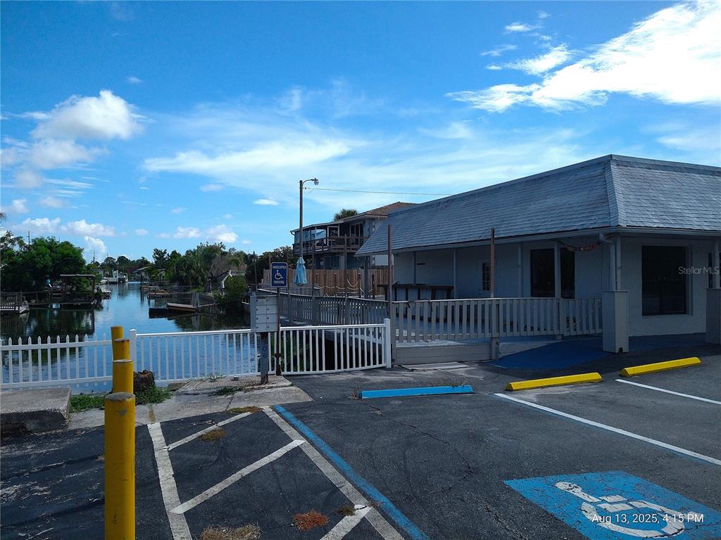 A building exterior with a waterfront deck, white fence, and a handicap parking space — 6920,6922,6924,6926,6928 CLARK STREET, HUDSON, FL