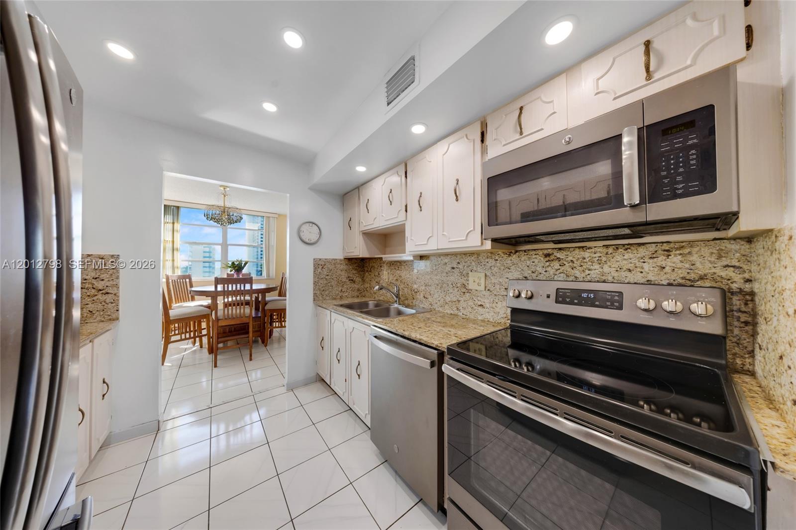 A kitchen features white cabinets, granite countertops, stainless steel appliances, and tile flooring — 3113 S Ocean Dr # 506, Hallandale Beach FL 33009, HALLANDALE BEACH, FL