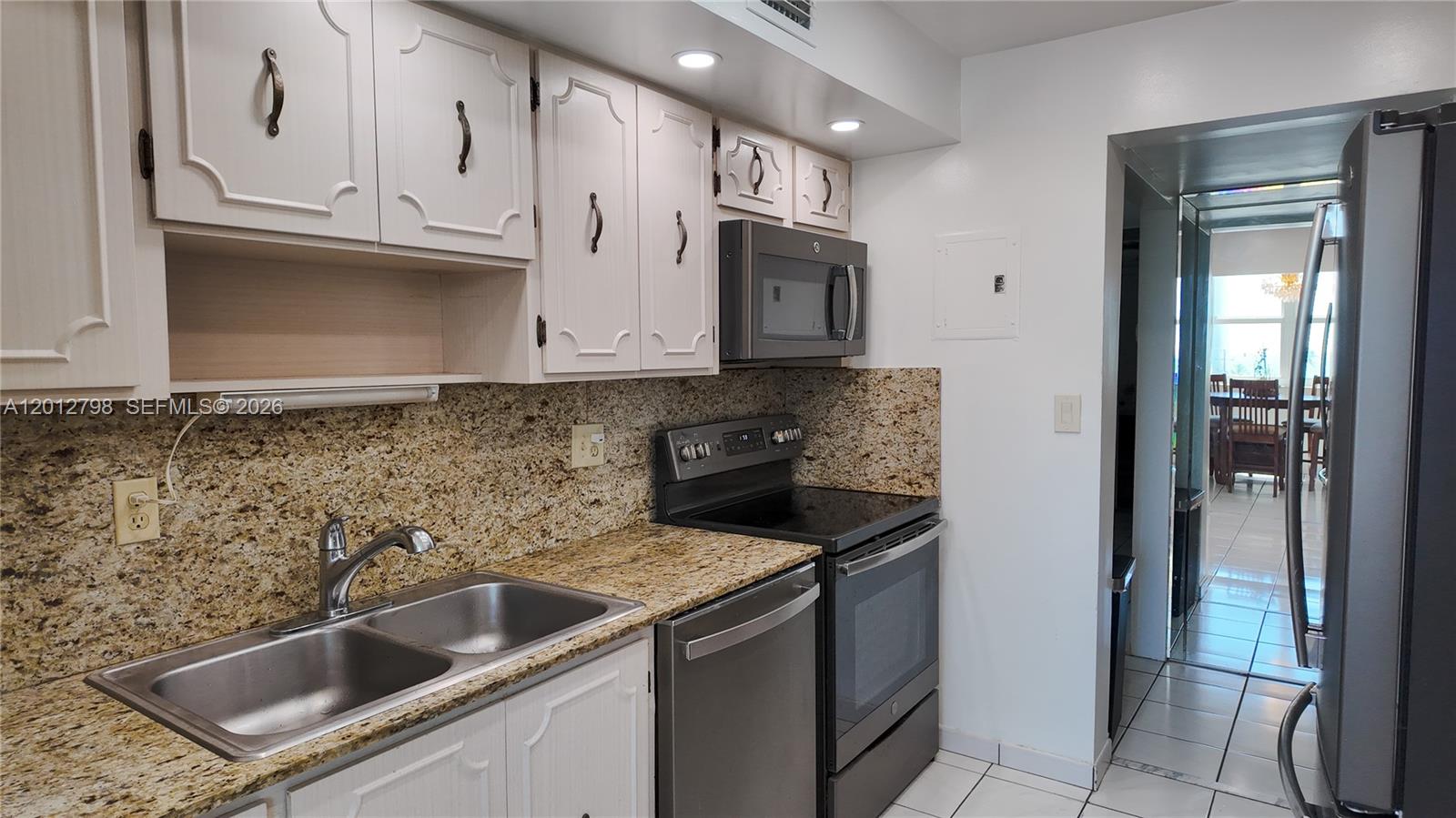 A kitchen features white cabinets, granite countertops, stainless steel appliances, and a double sink — 3113 S Ocean Dr # 506, Hallandale Beach FL 33009, HALLANDALE BEACH, FL