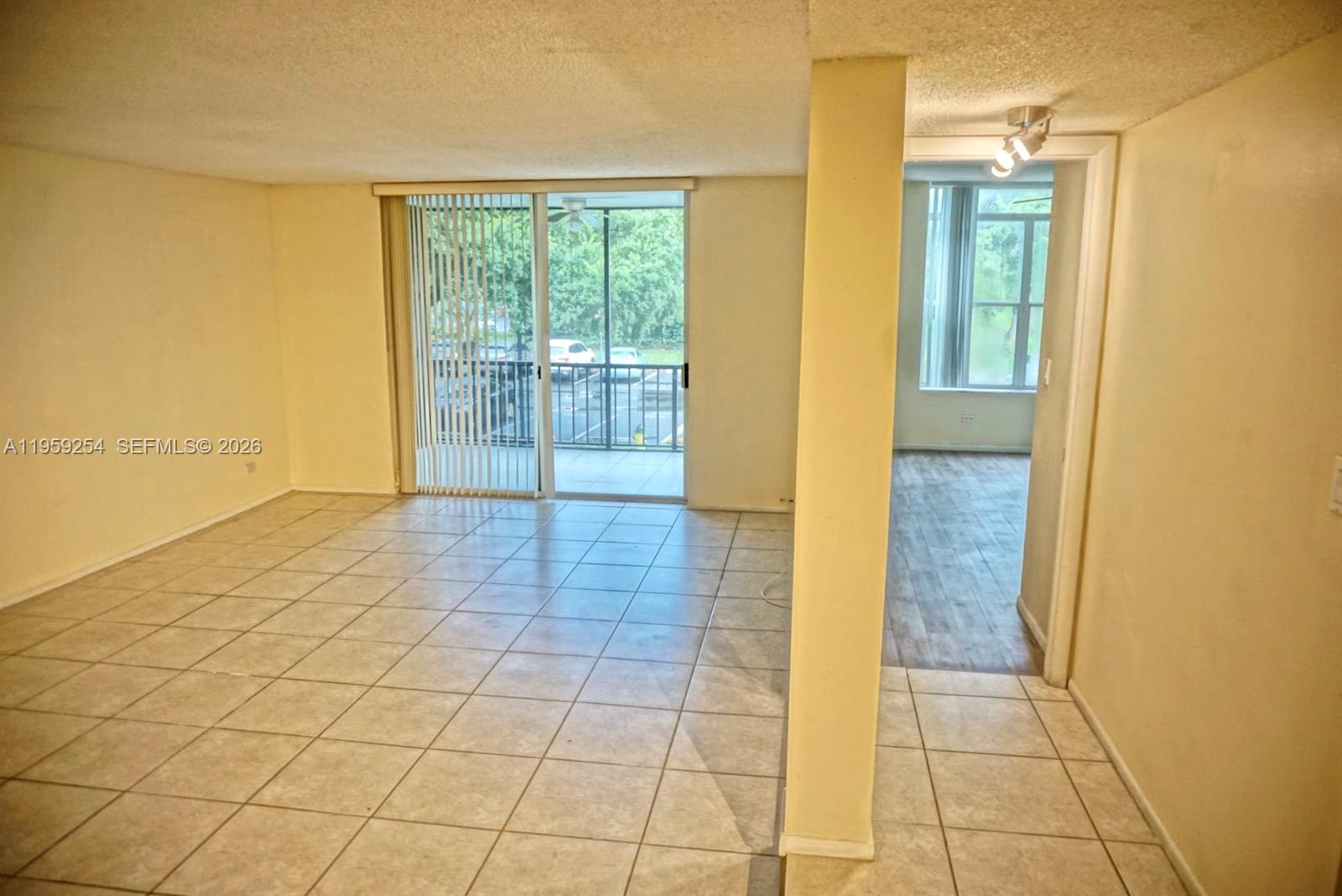 A living area with tile flooring leads to a balcony through sliding glass doors — 3740 Inverrary Dr # 2N, Lauderhill FL 33319, LAUDERHILL, FL