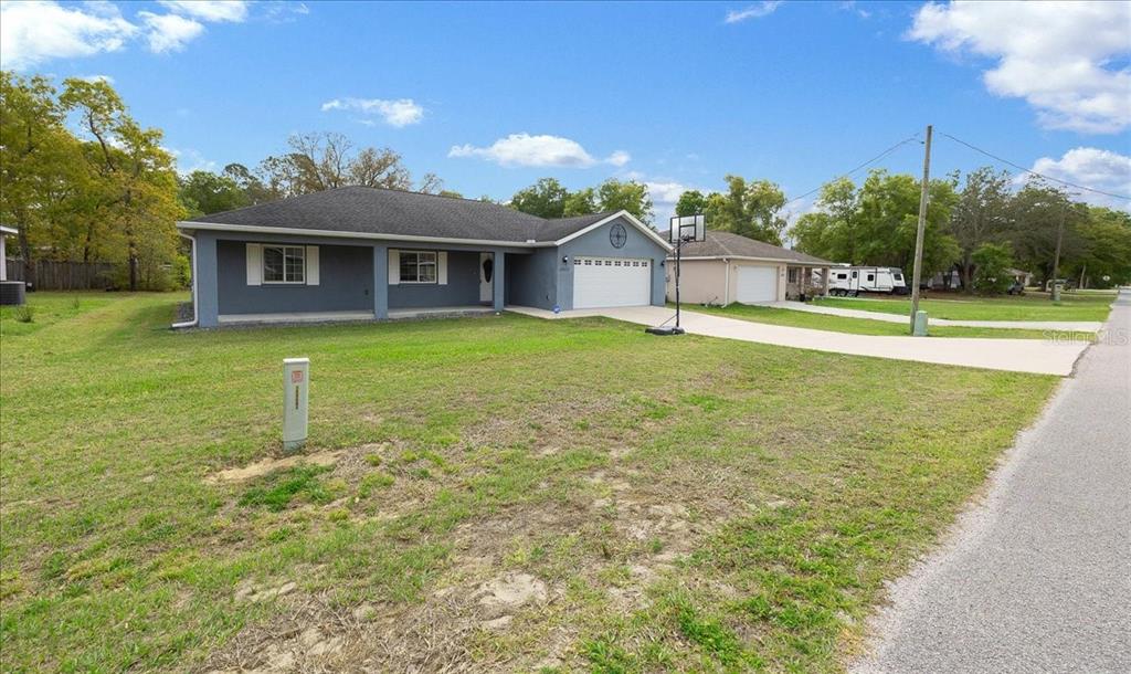 A single-story gray house with a covered front porch and an attached two-car garage — 15675 SE 89TH TERRACE, SUMMERFIELD, FL