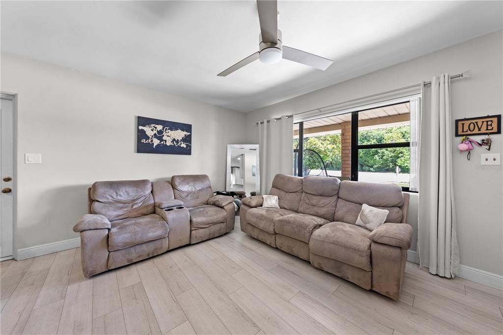 A living room features light wood-look flooring, two brown reclining sofas, and a ceiling fan — 1712 PATRICK STREET, KISSIMMEE, FL
