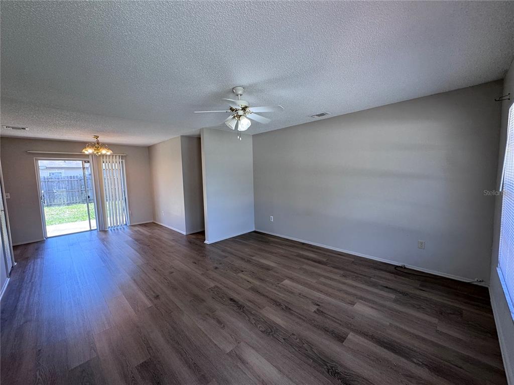 A living room features wood-look flooring, a ceiling fan, and a sliding glass door — 321 NOTHERN DURANGO AVENUE, OCOEE, FL