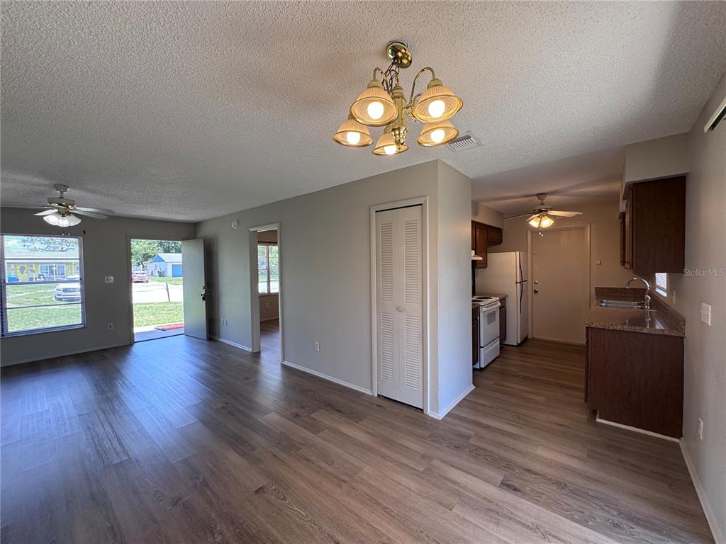 An open-concept living area with wood-look flooring, a kitchen, and a ceiling chandelier — 321 NOTHERN DURANGO AVENUE, OCOEE, FL