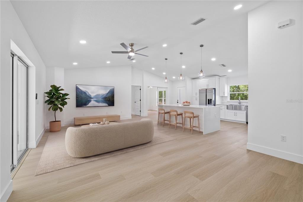 An open-concept living room and kitchen featuring light wood floors, white cabinetry, and a sofa — 8157 N VOYAGER DRIVE, CITRUS SPRINGS, FL
