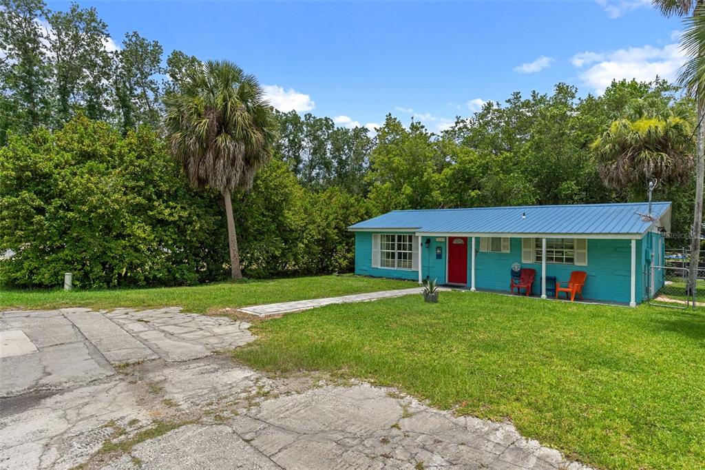 A turquoise single-story house with a blue metal roof and a red front door — 7280 WIMBERLY COURT, WEEKI WACHEE, FL