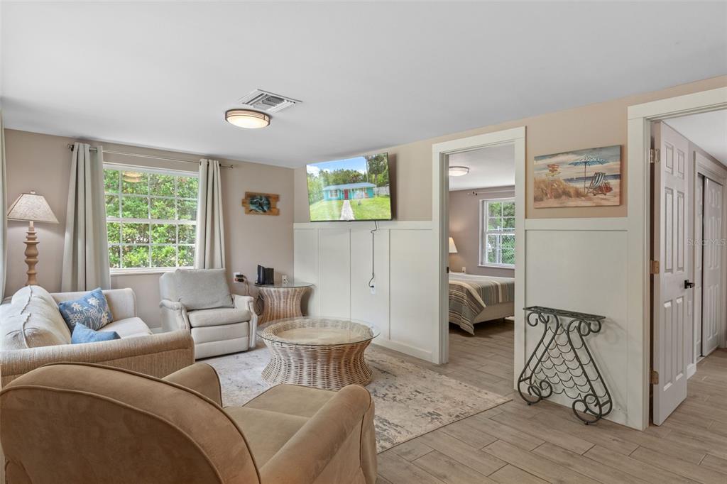 A living room features beige walls, white wainscoting, a wicker coffee table, and tiled floors — 7280 WIMBERLY COURT, WEEKI WACHEE, FL