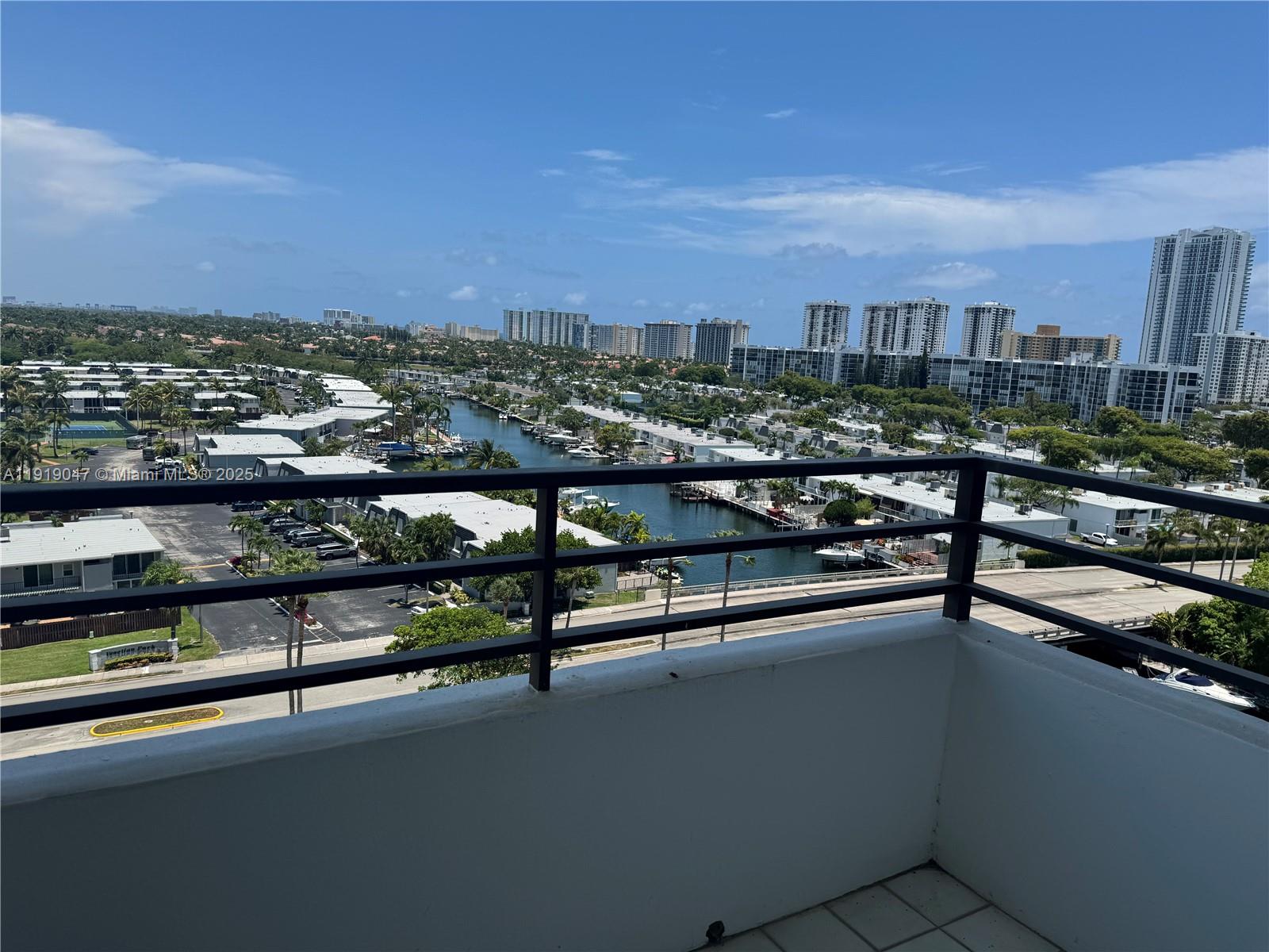 A balcony with a black metal railing overlooks a canal, residential buildings, and city skyline — 2500 Parkview Dr # 1109, Hallandale Beach FL 33009, HALLANDALE BEACH, FL