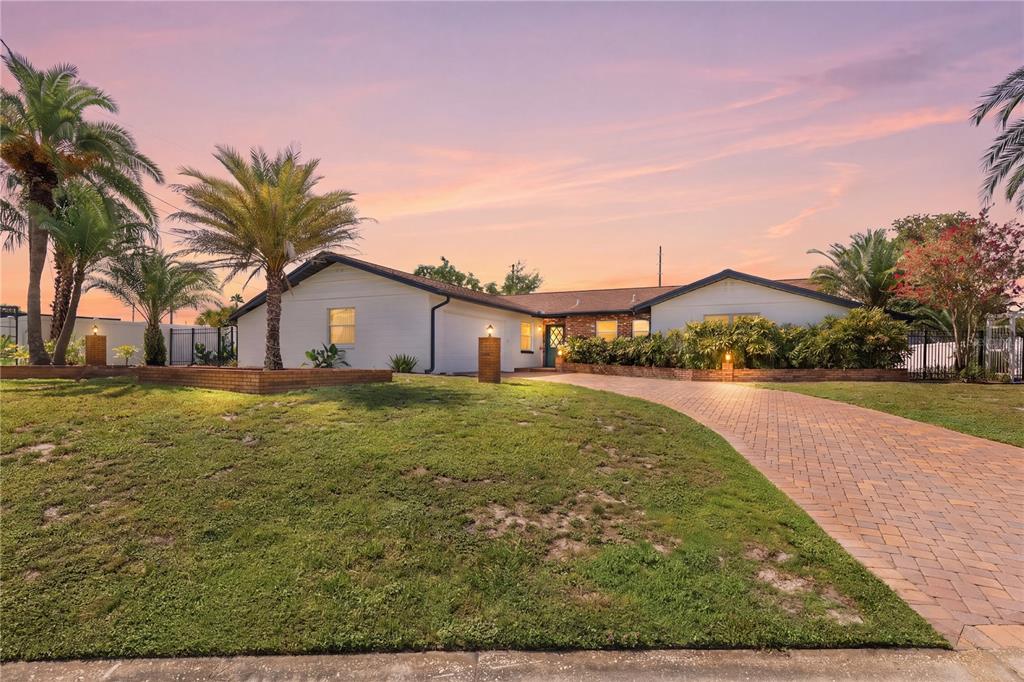 A white house with a brick accent wall, a teal front door, and a paver driveway — 2826 AMBERGATE ROAD, WINTER PARK, FL