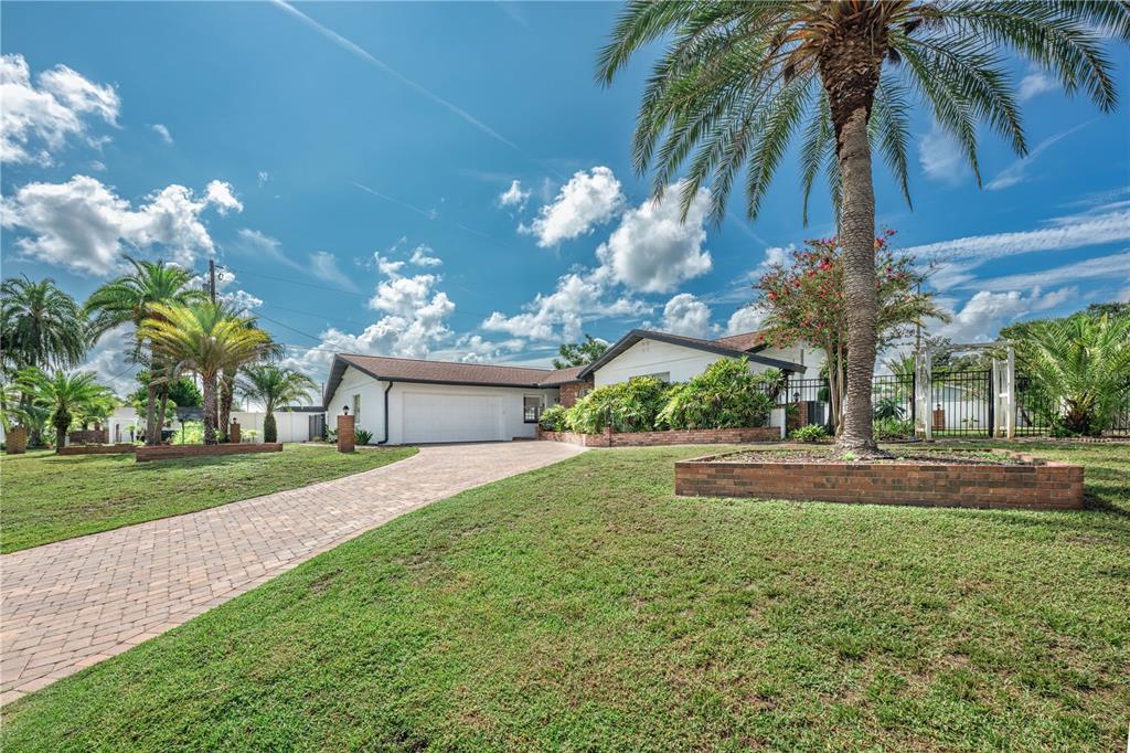 A brick and white block exterior features a green front door and a paved entryway — 2826 AMBERGATE ROAD, WINTER PARK, FL