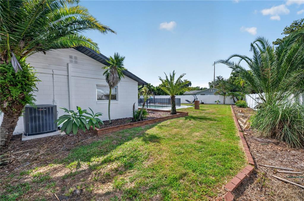 A backyard features a white house, a swimming pool, palm trees, and a brick-edged lawn — 2826 AMBERGATE ROAD, WINTER PARK, FL