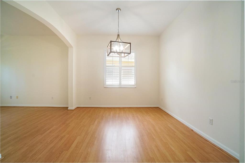 An empty dining room features light wood flooring, beige walls, and a hanging lantern chandelier — 974 KERSFIELD CIRCLE, LAKE MARY, FL