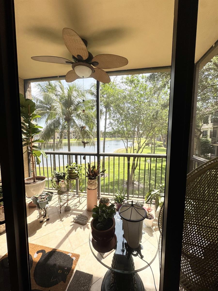 A screened-in balcony features a ceiling fan, potted plants, and a view of a lake — 6720 Coral Lake Drive # 6720, Margate FL 33063, MARGATE, FL