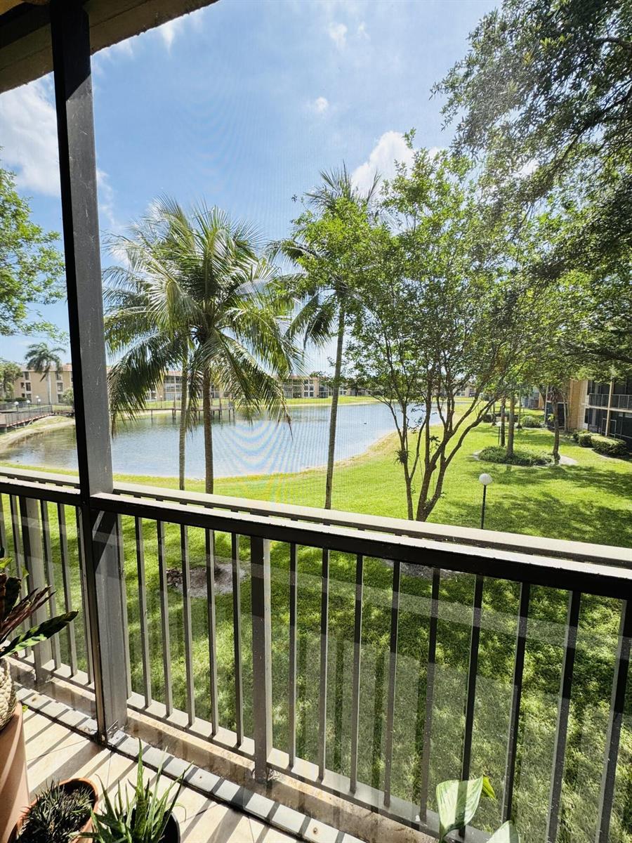 A view of a lake and green lawn from a screened-in balcony — 6720 Coral Lake Drive # 6720, Margate FL 33063, MARGATE, FL