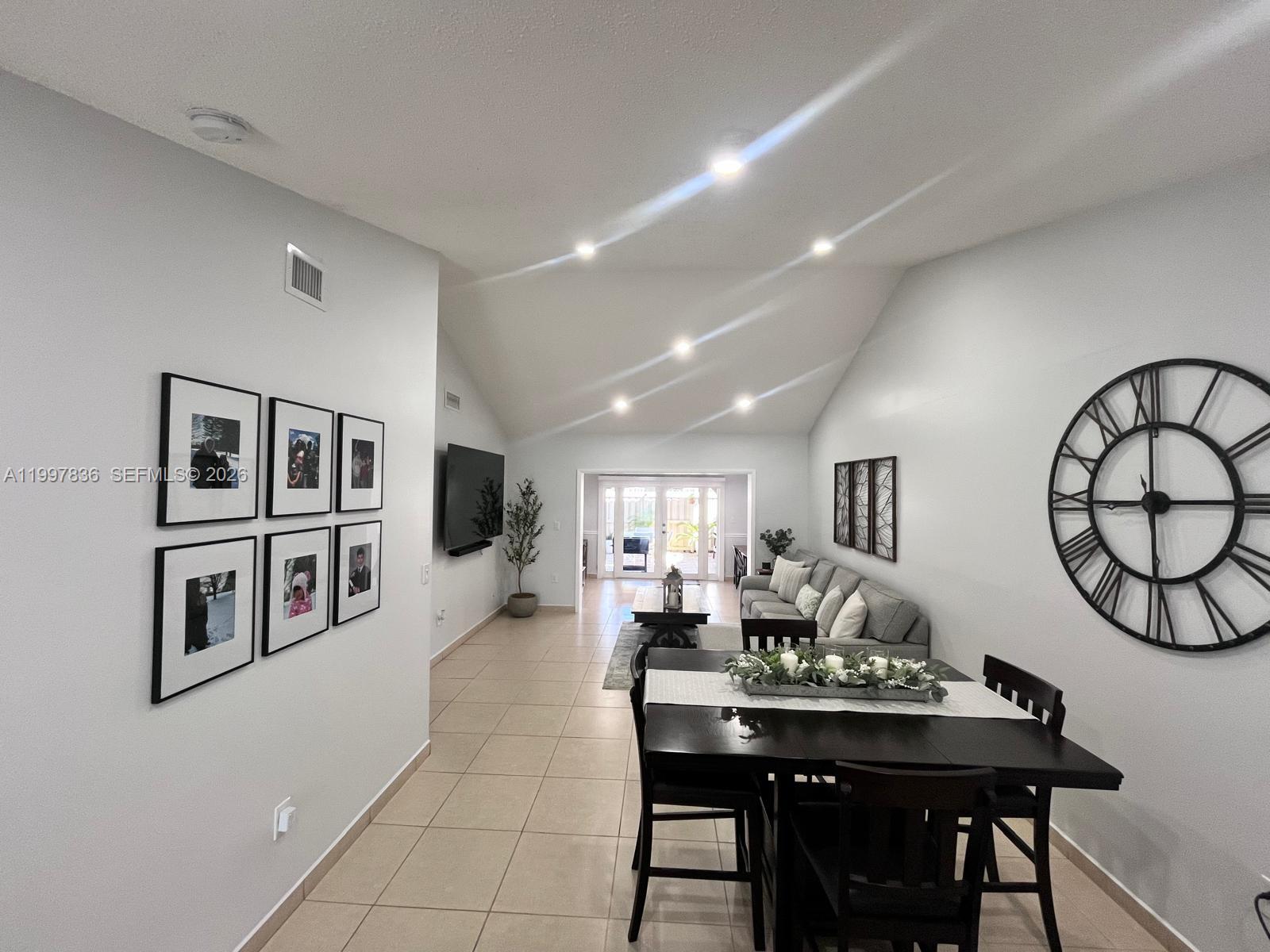 A dining area and living room with vaulted ceilings, tile floors, and neutral walls — 4533 SW 143rd Pl, Miami FL 33175, MIAMI, FL