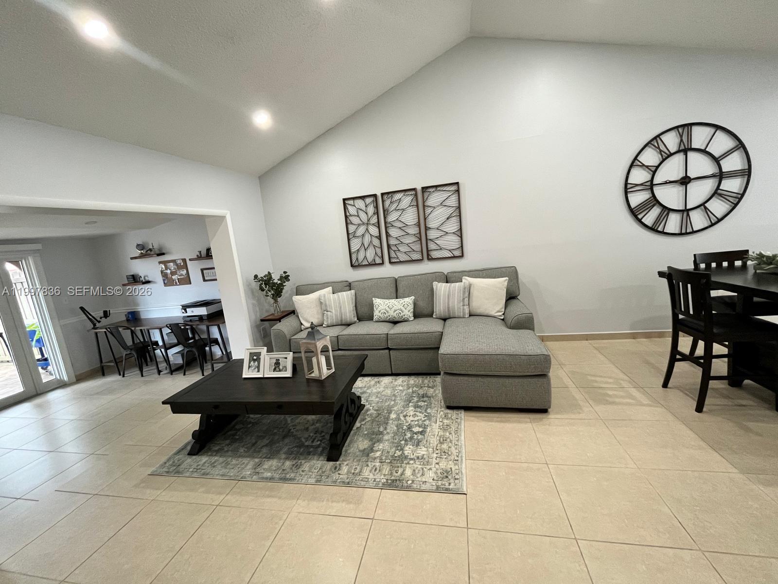 A living room features a gray sectional sofa, a dark coffee table, and a large clock — 4533 SW 143rd Pl, Miami FL 33175, MIAMI, FL